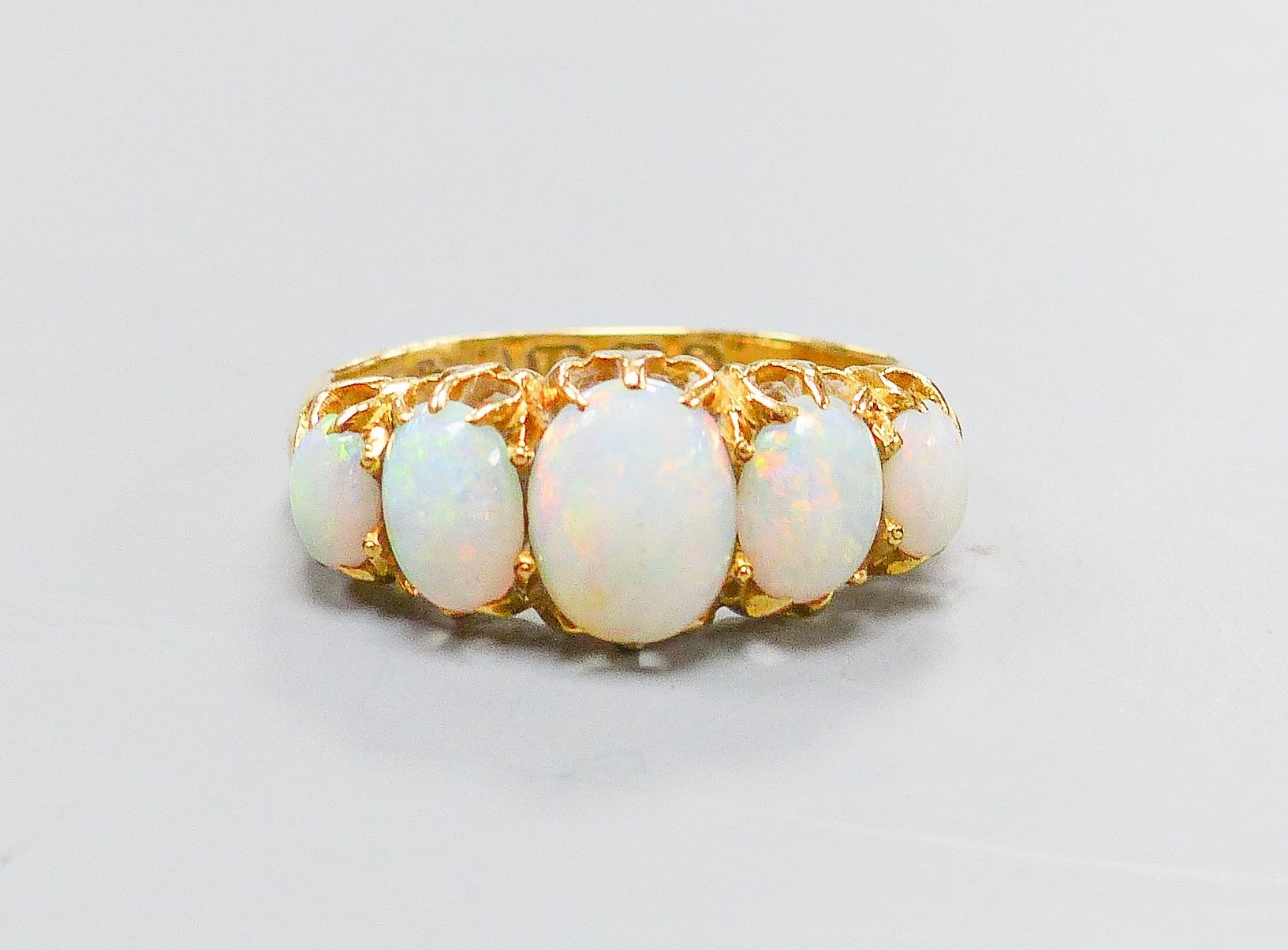 An Edwardian 18ct gold and graduated five stone white opal set half hoop ring, size K, gross 3.8 grams.